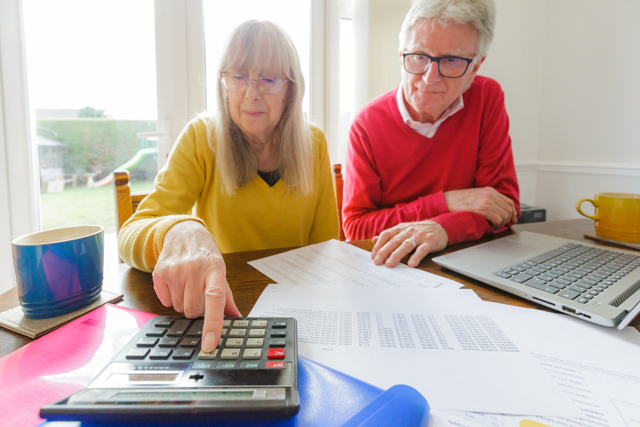 older couple looking at documents together and punching numbers into a calculator