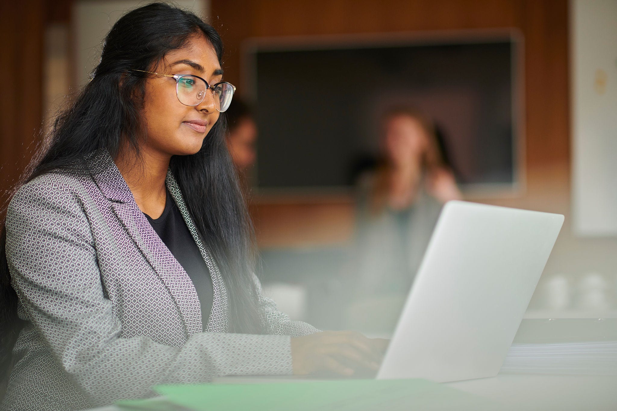 young woman dressed professionally working at a laptop