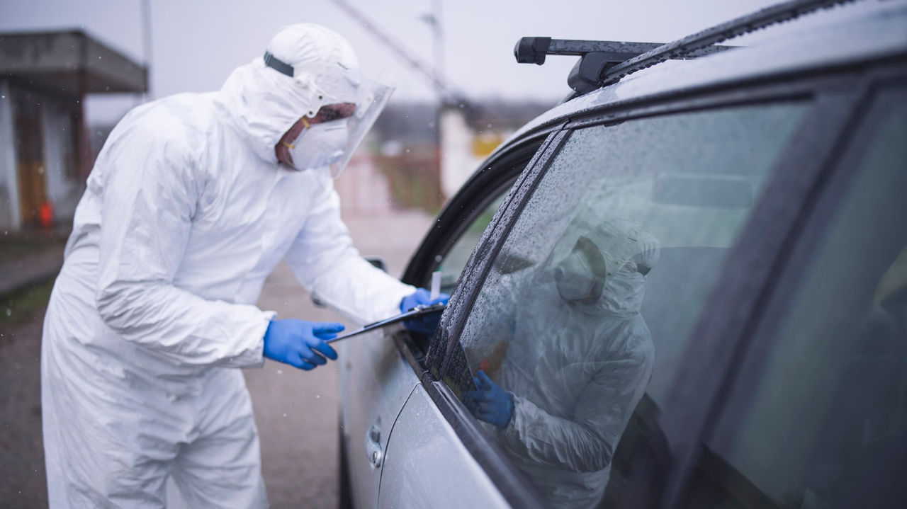A man in a protective suit looking at a car.
