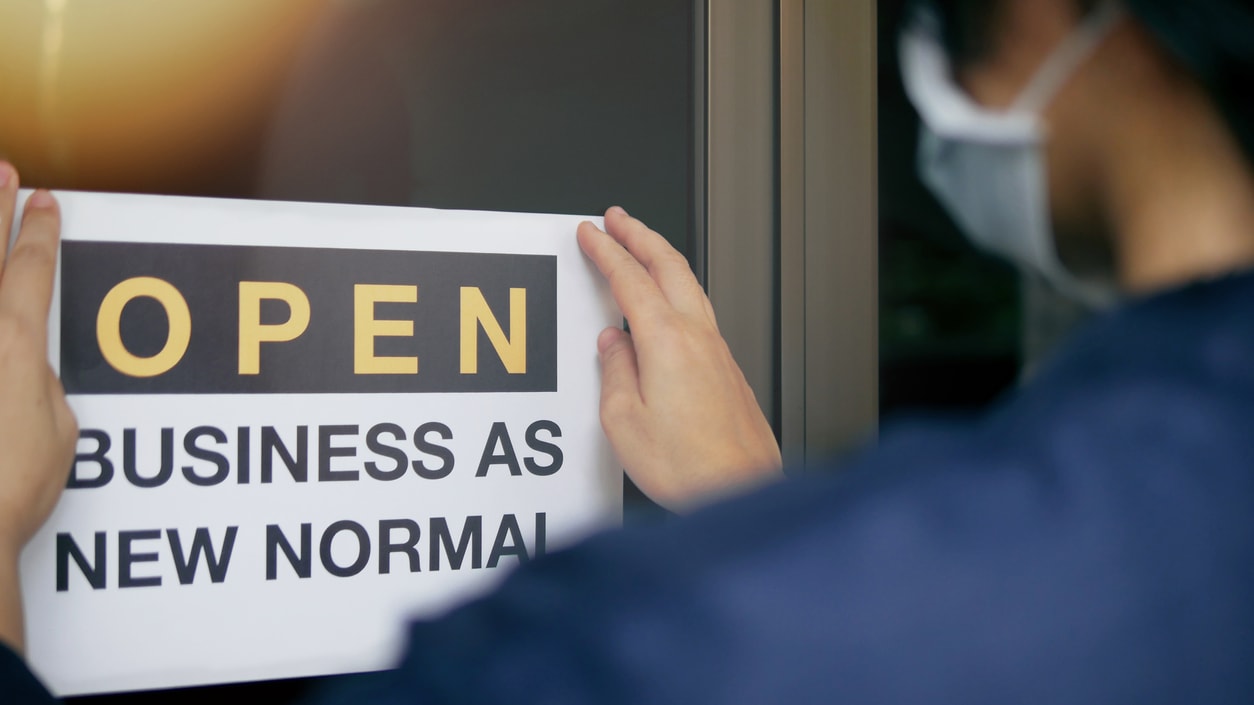 A person holding a sign that says open business as new normal.
