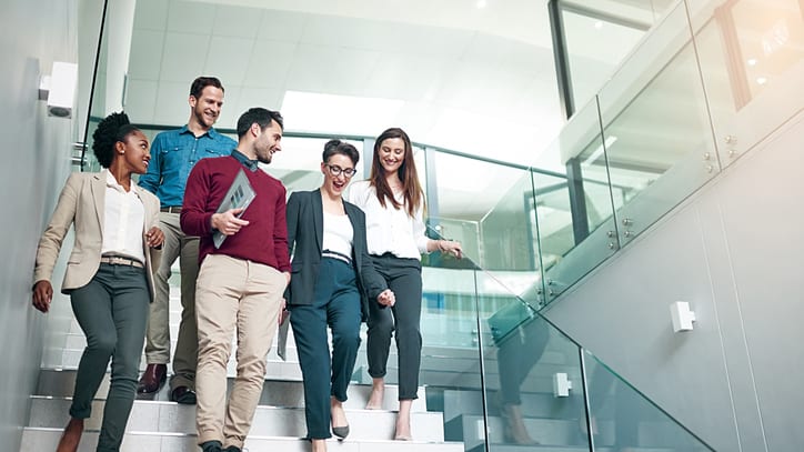 A group of business people walking up stairs in an office.