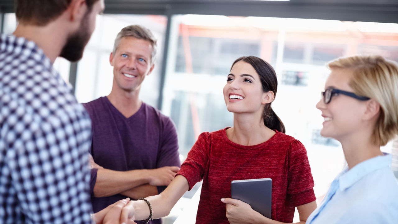 Smiling woman shakes hand of new work colleague. 
