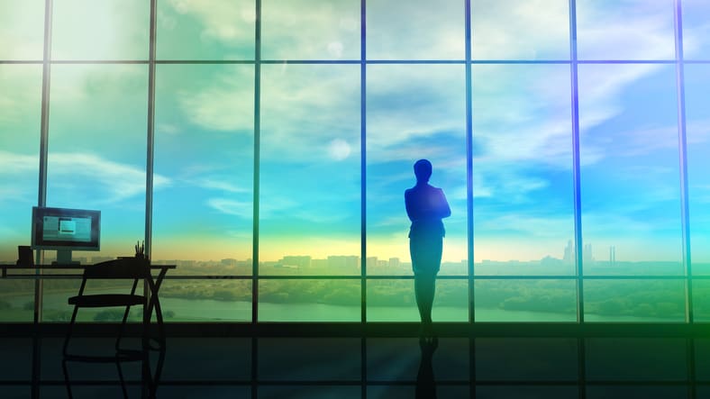 A silhouette of a businessman standing in front of a window.