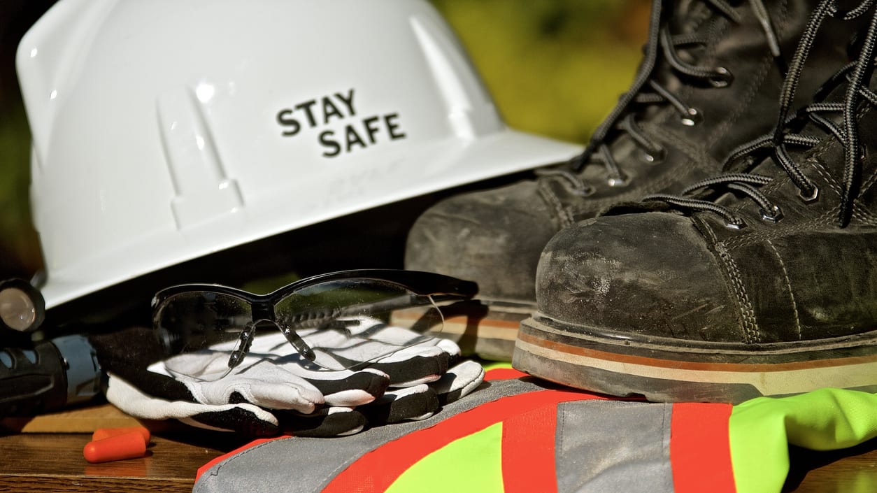 A hard hat, safety glasses, and safety goggles sit on a table.