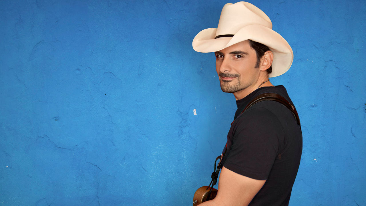 Brad Paisley in a cowboy hat holding a guitar.