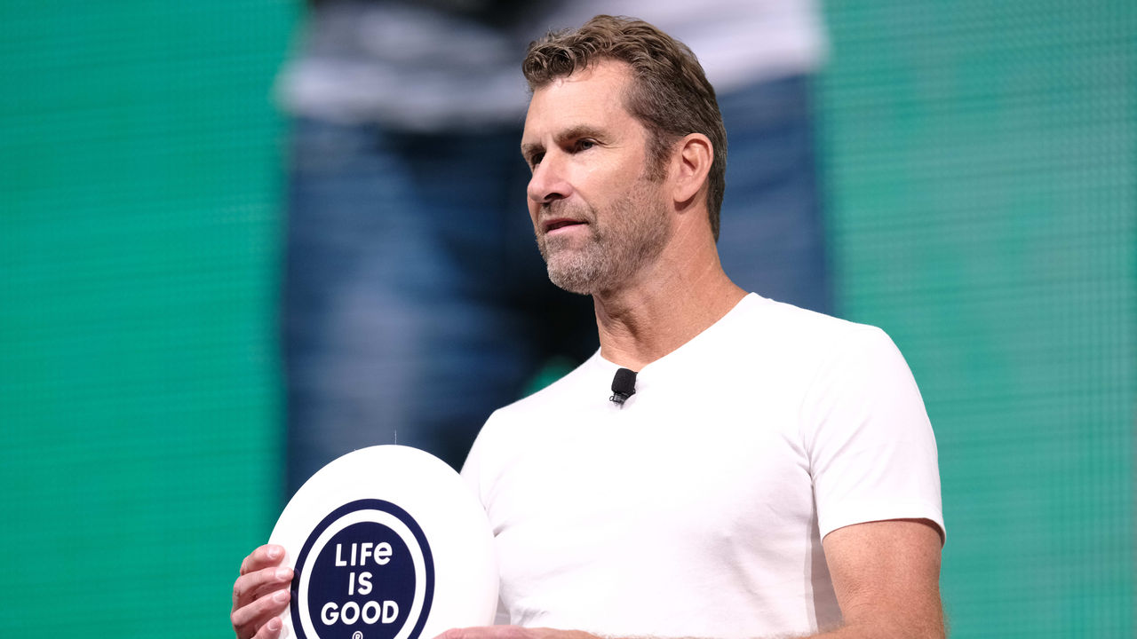 A man holding up a white frisbee on a stage.