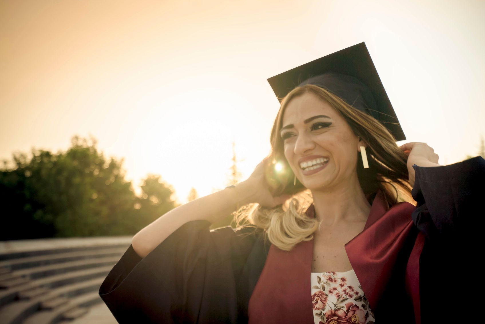 Young woman graduate with her cap and gown on a college campus