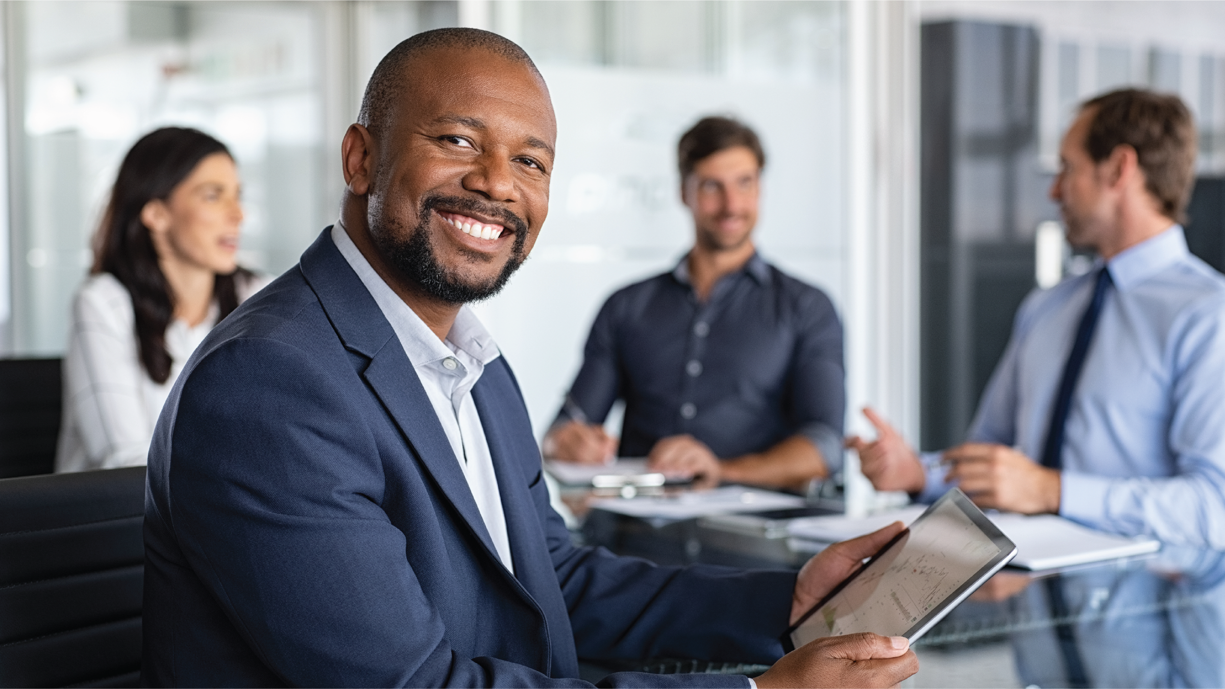 Smiling man with coworkers in background Smiling man with coworkers in background