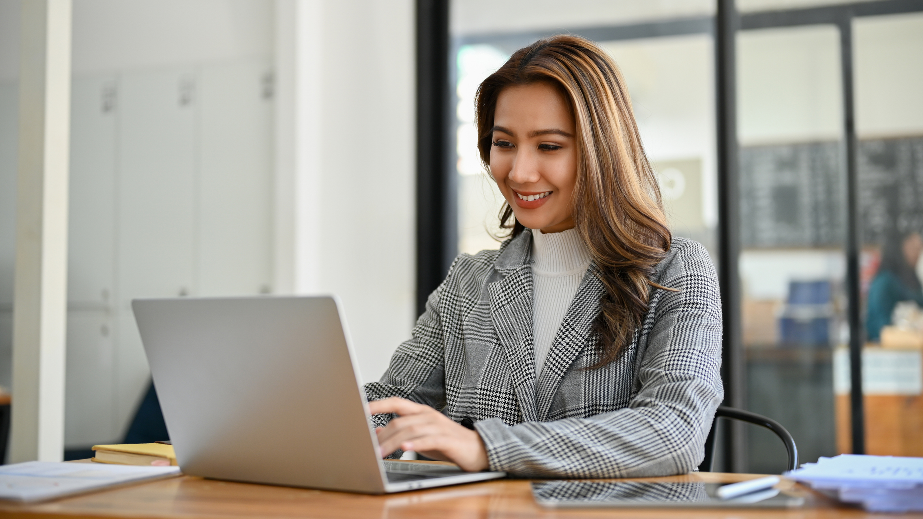 woman smiles while using laptop in an office