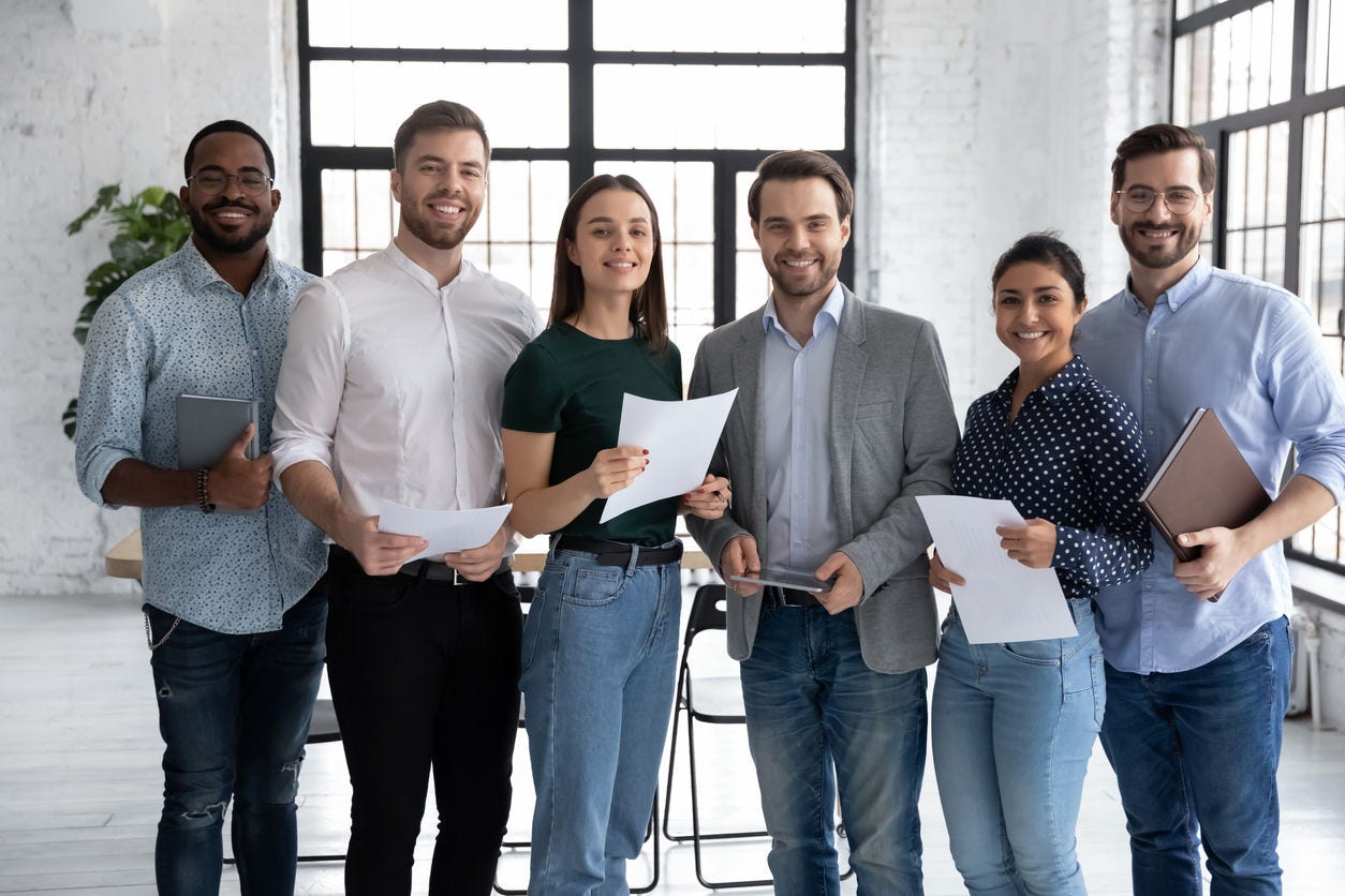 Portrait of happy diverse group of interns or students and corporate teacher after successfully passes exam. Multi ethnic business team of employees holding paper documents, looking at camera, smiling