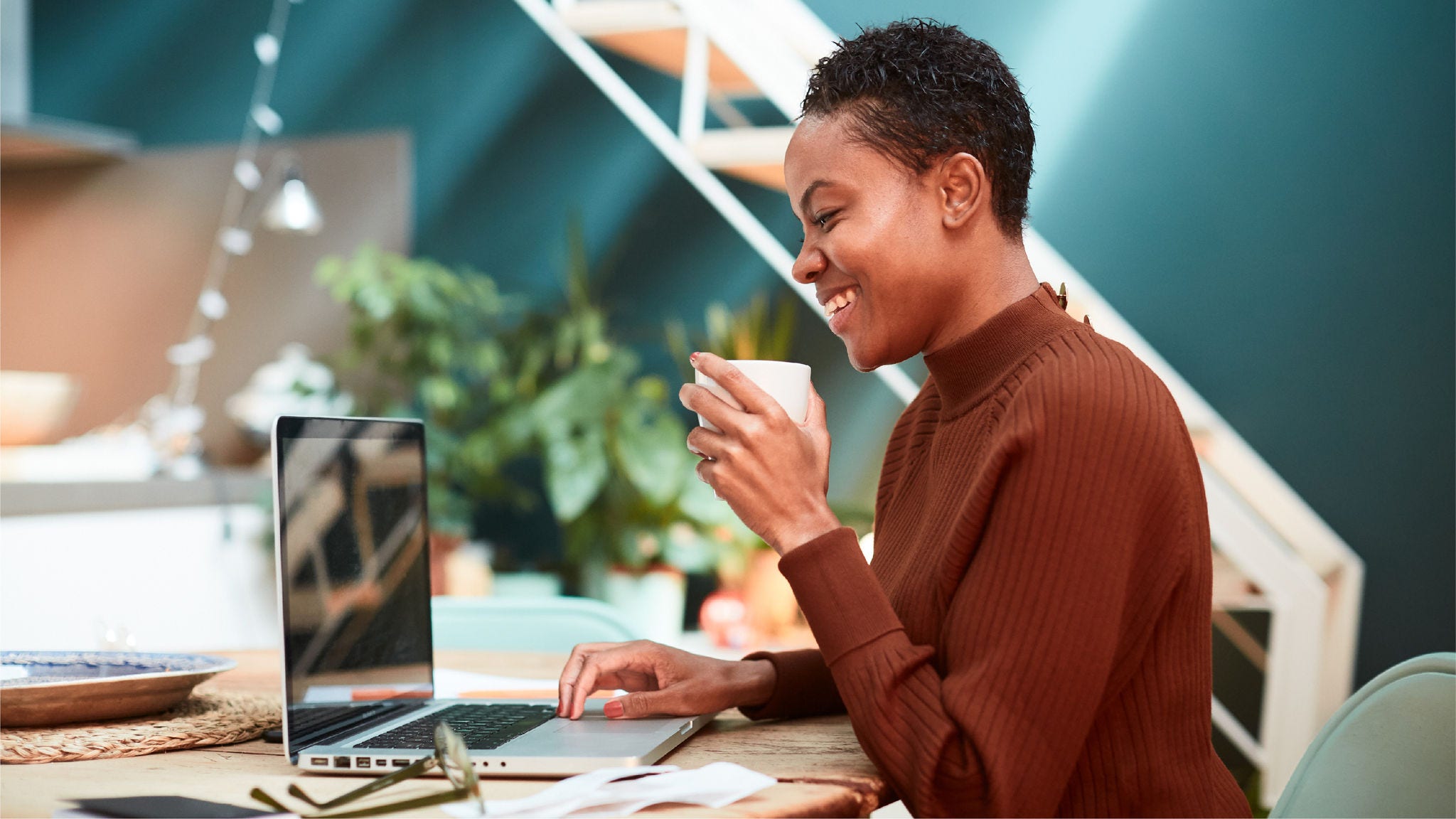 Woman laughs during an online meeting with her coffee. 