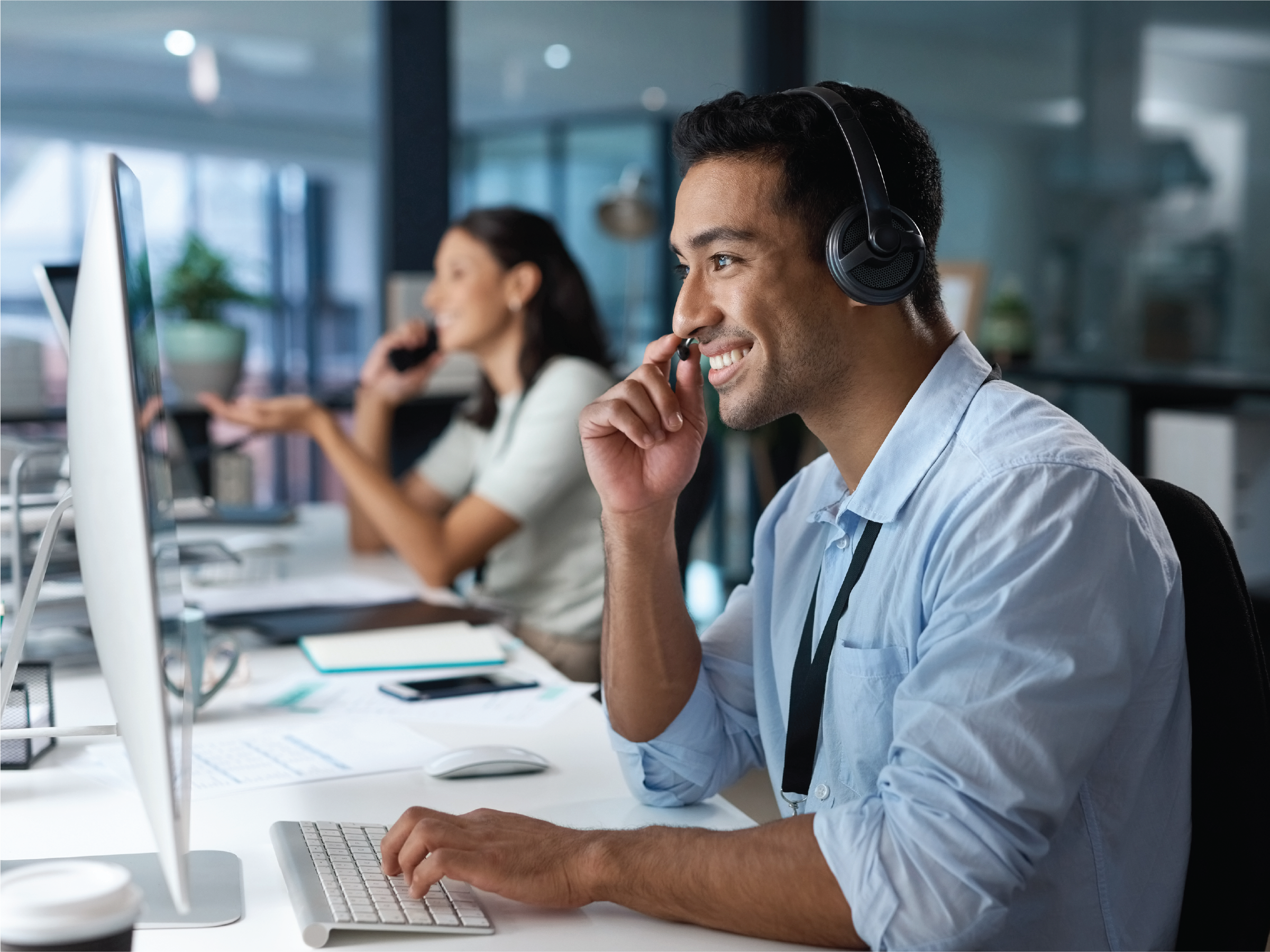 man in front of computer speaking on a headset