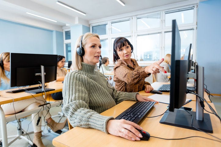 Mature female manager training trainee over computer at office