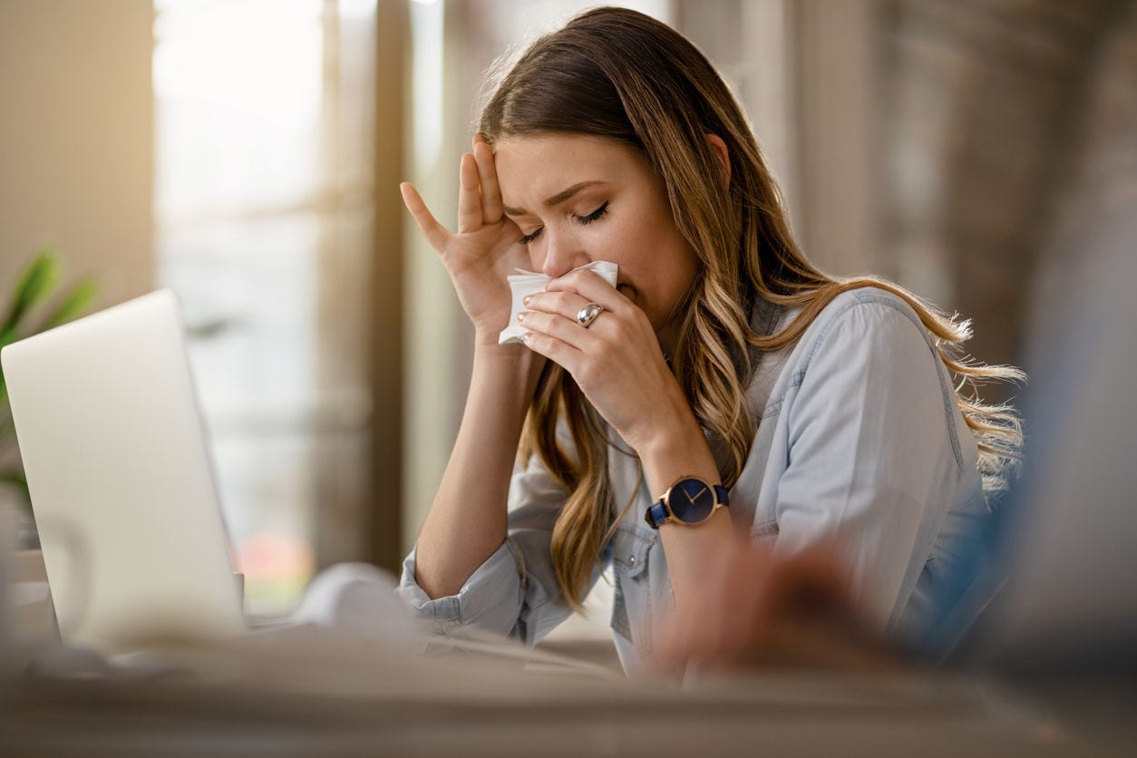Someone sneezing into a Kleenex while at their computer.