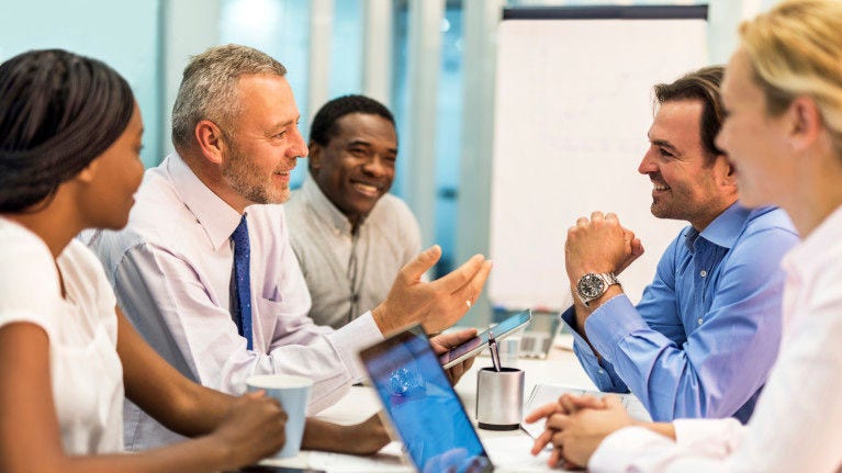 Business men and women at a conference table smiling