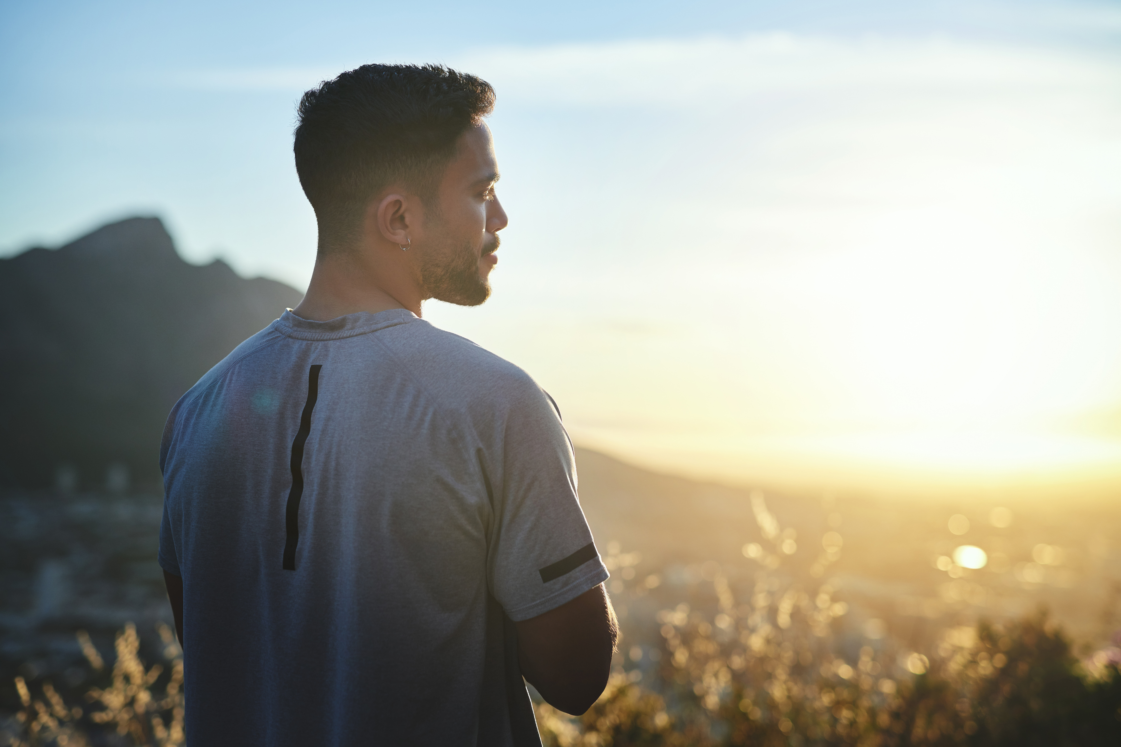 man looking towards sunrise in mountain meadow