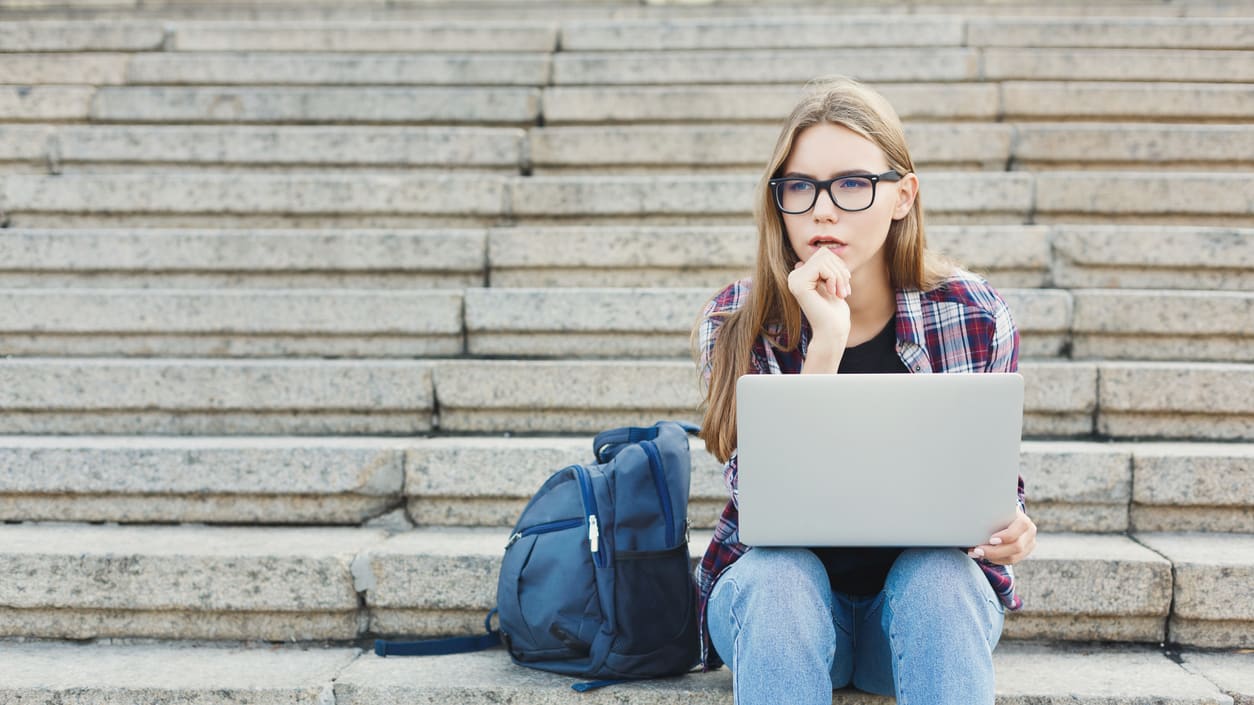 A young woman sitting on the steps with a laptop.