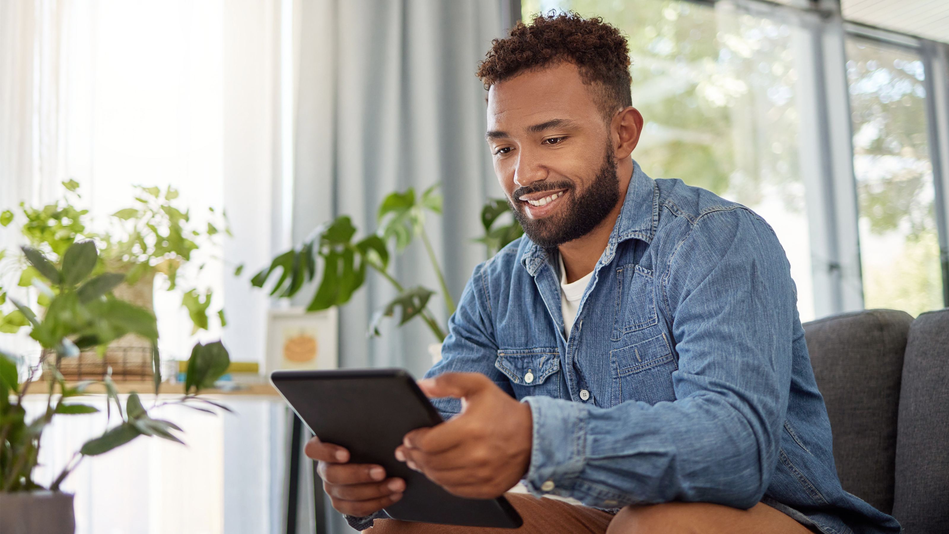 man smiles while using tablet at home