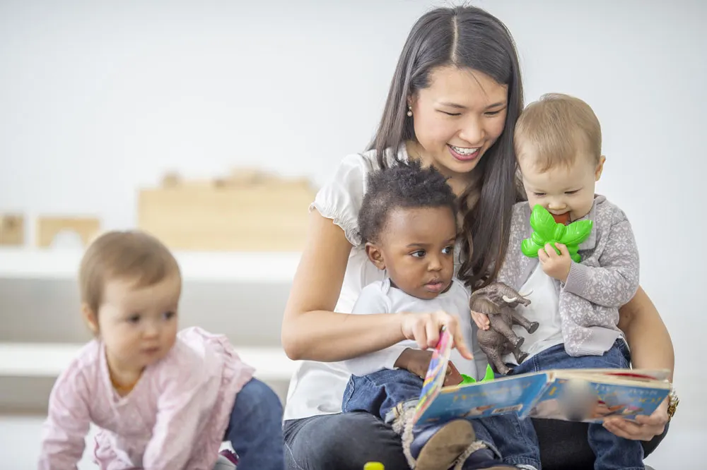 woman reading a book to 3 toddlers