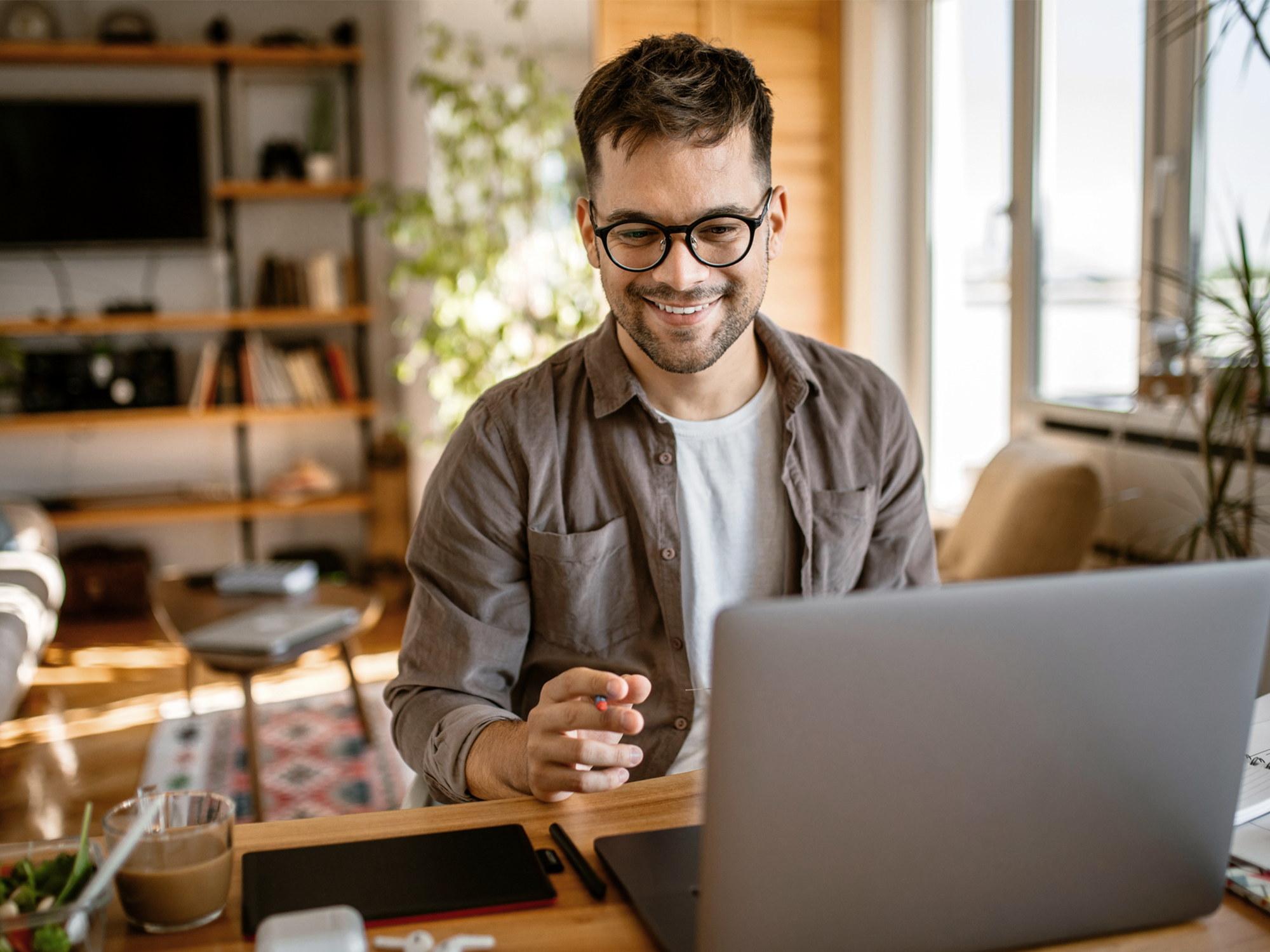 man smiles while working from home with his laptop