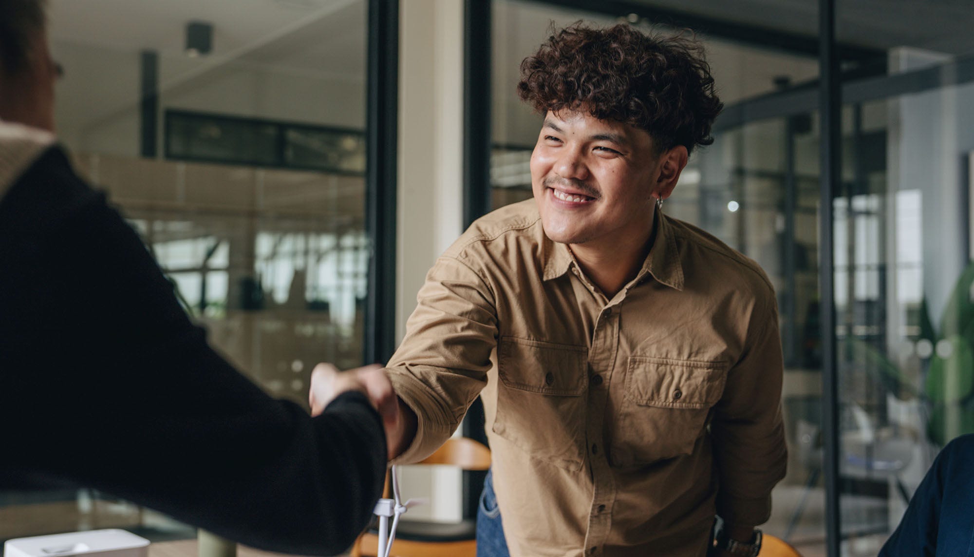 young smiling man shaking executive's hand