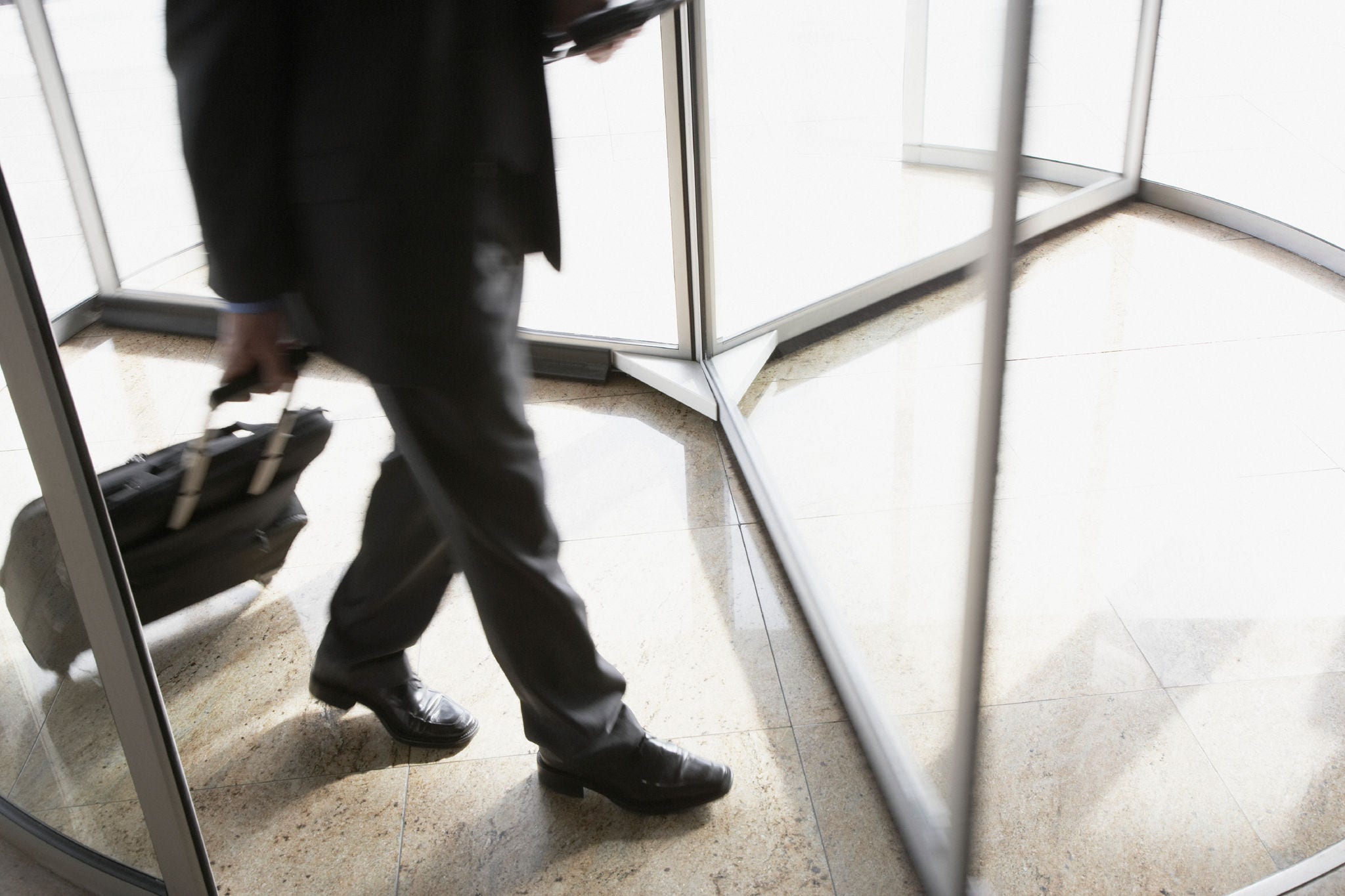 Businessman with suitcase using revolving door