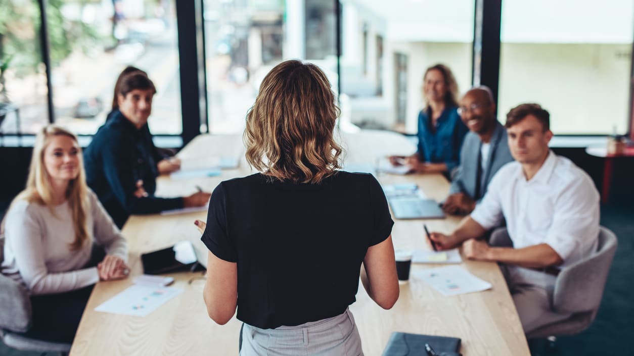 woman presents to a group of people at a conference table