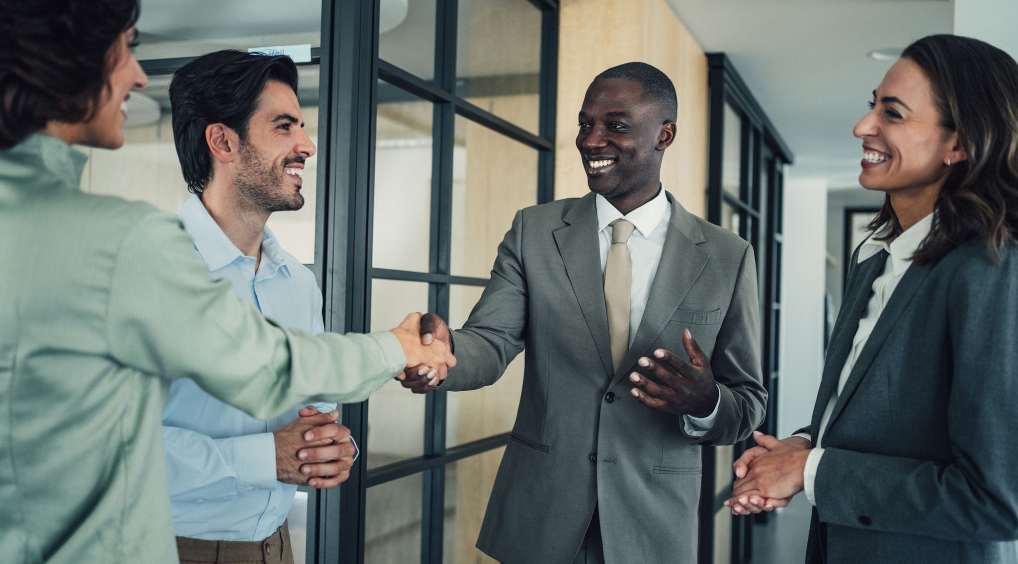 colleagues welcoming new coworker shaking hands and smiling