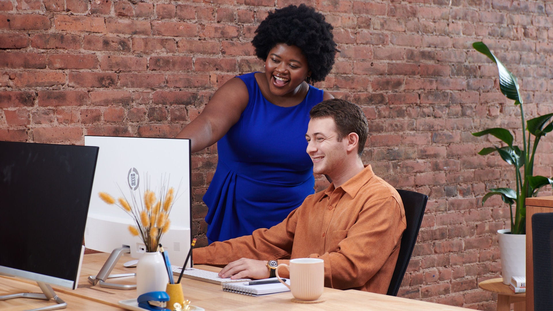 Two colleagues share a laugh about something on the computer.