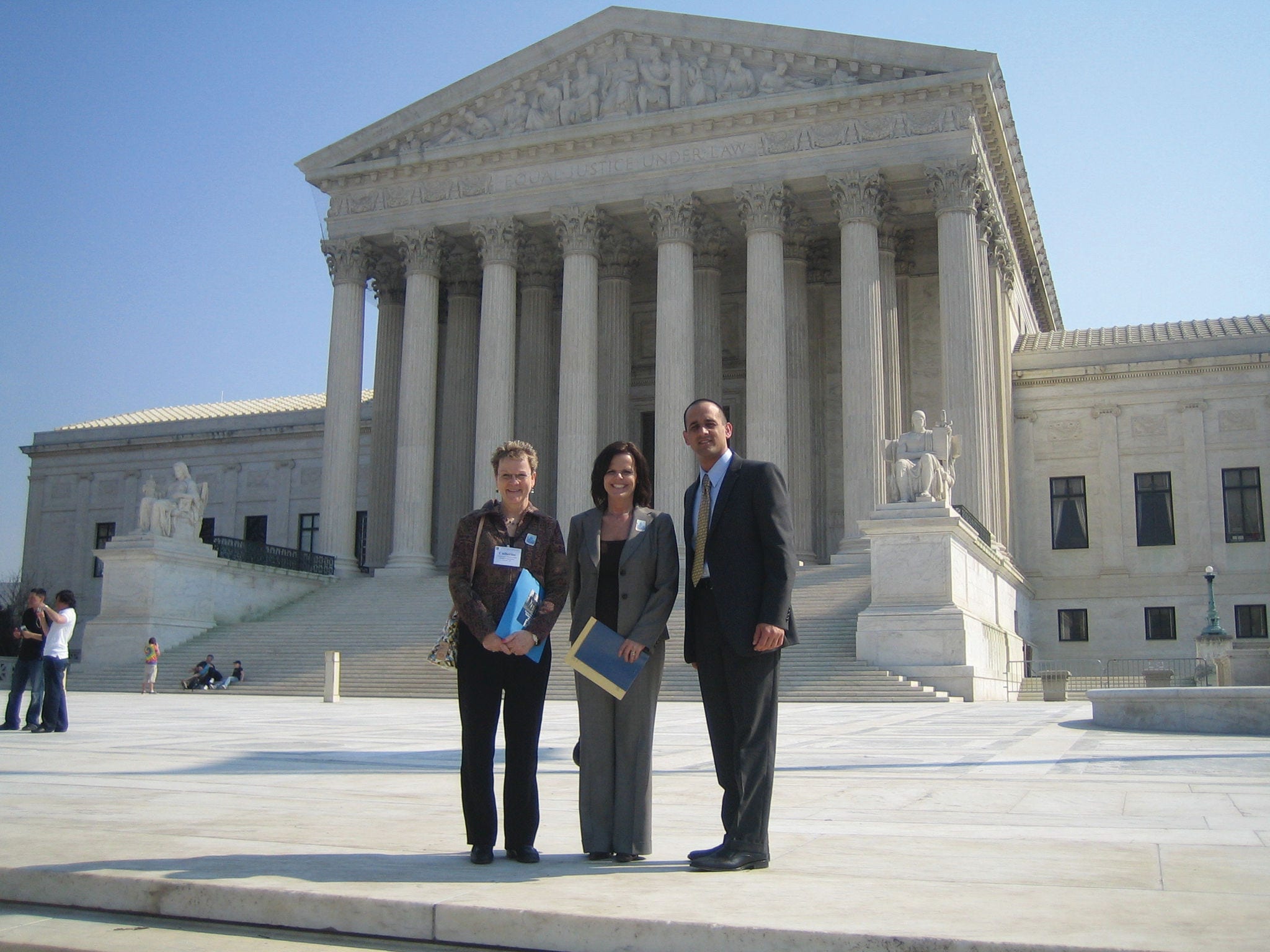 three people posing in front of the supreme court