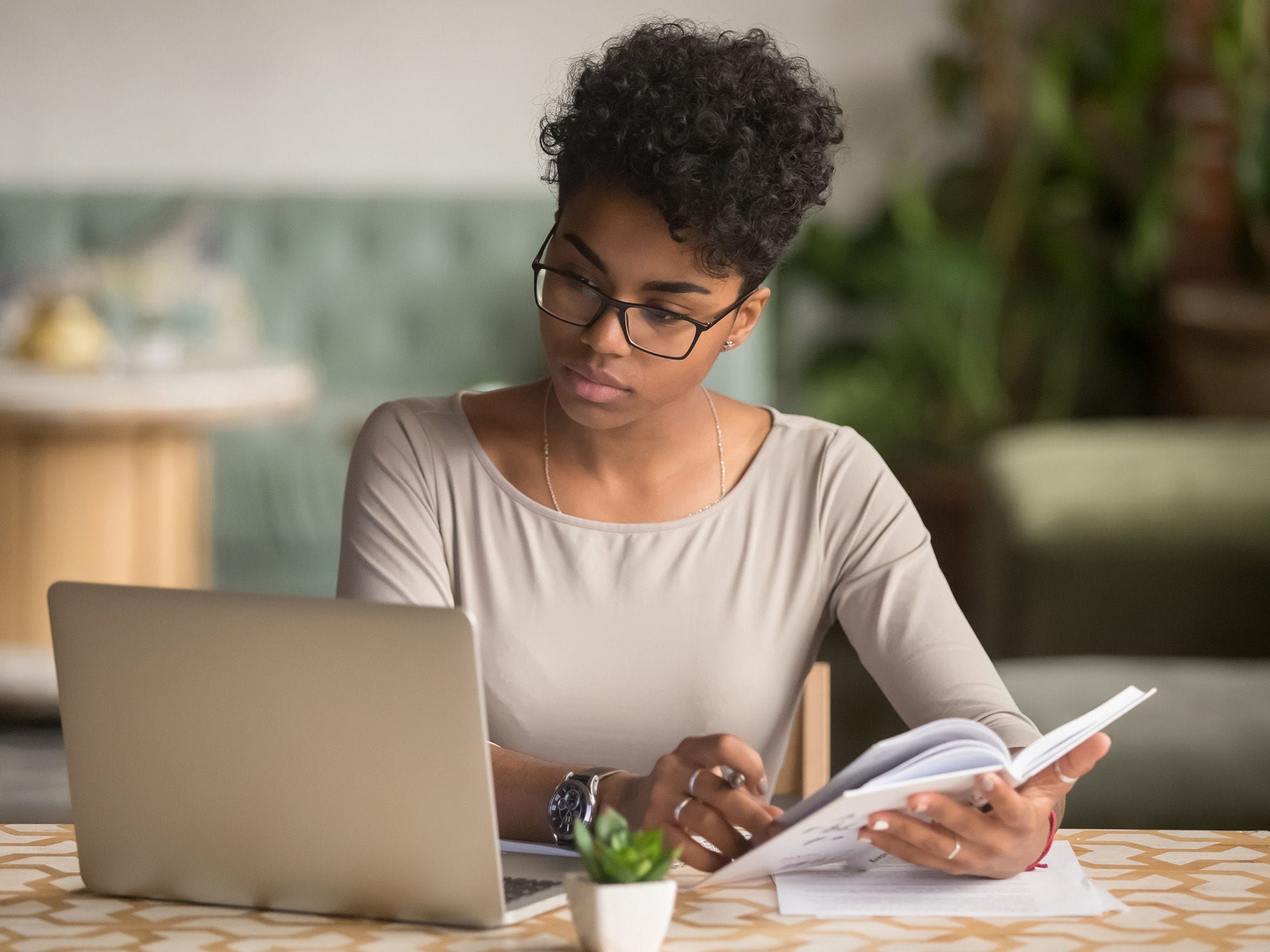 Woman studies on her laptop with her notebook.