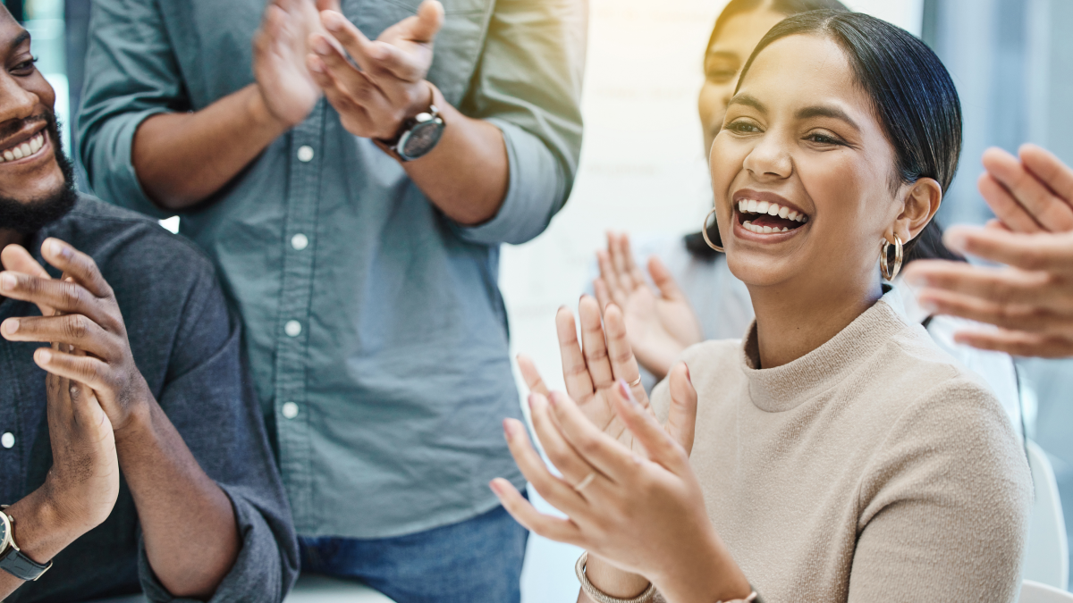 group of people clapping with a woman framed at the center