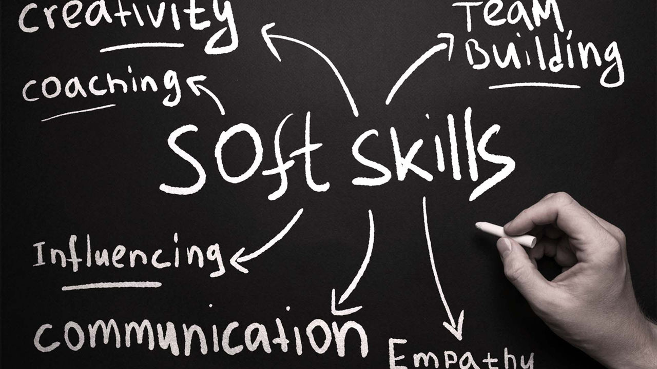 A hand writing the word soft skills on a blackboard.