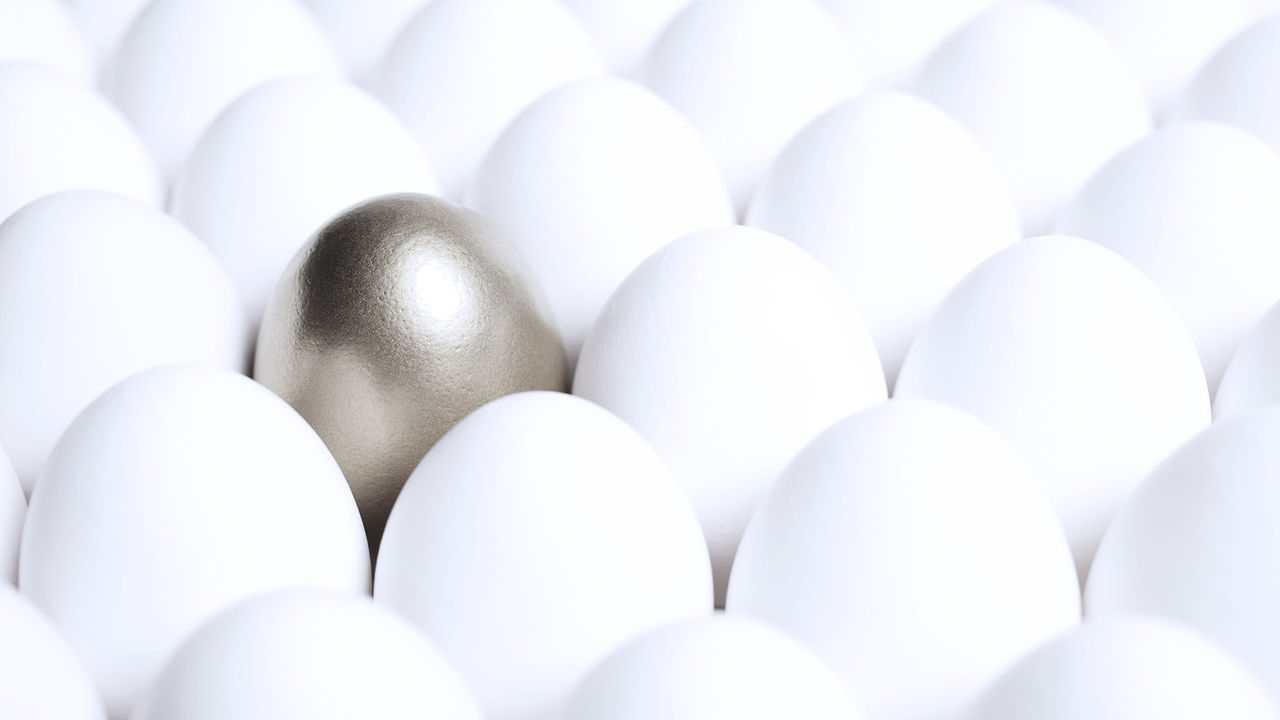 A gold egg in a group of white eggs.