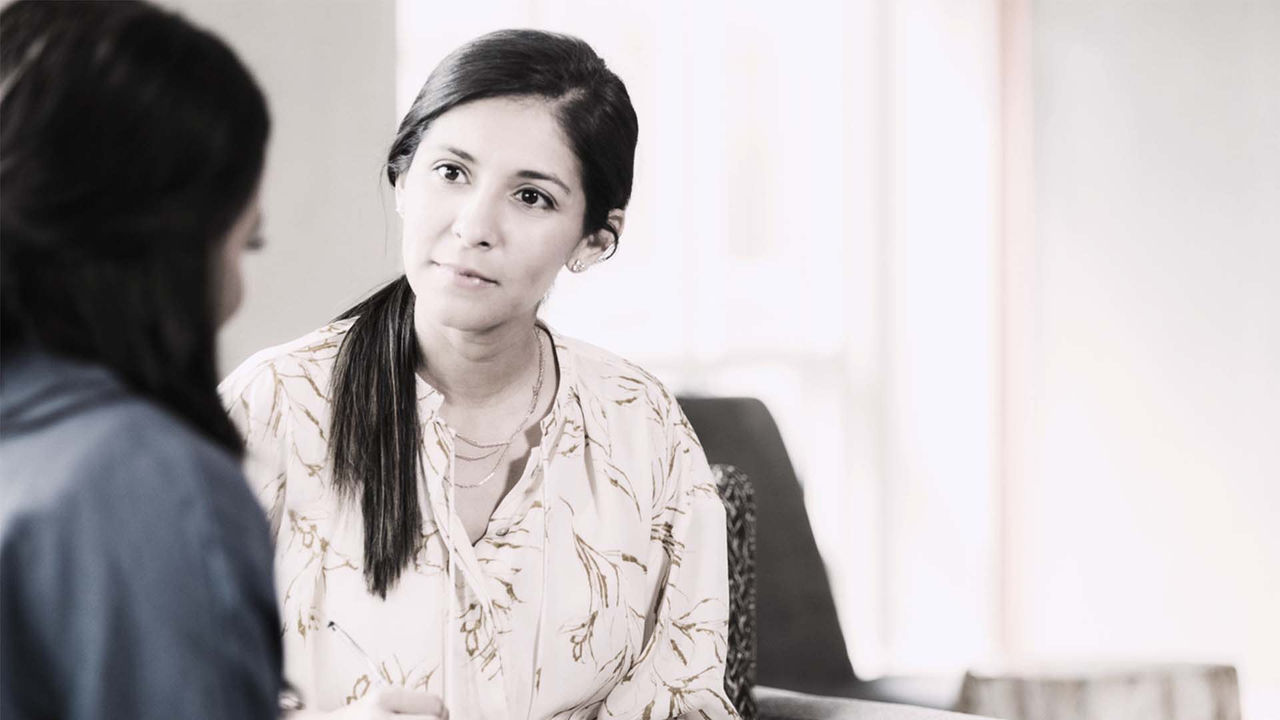 A woman talking to another woman in an office.