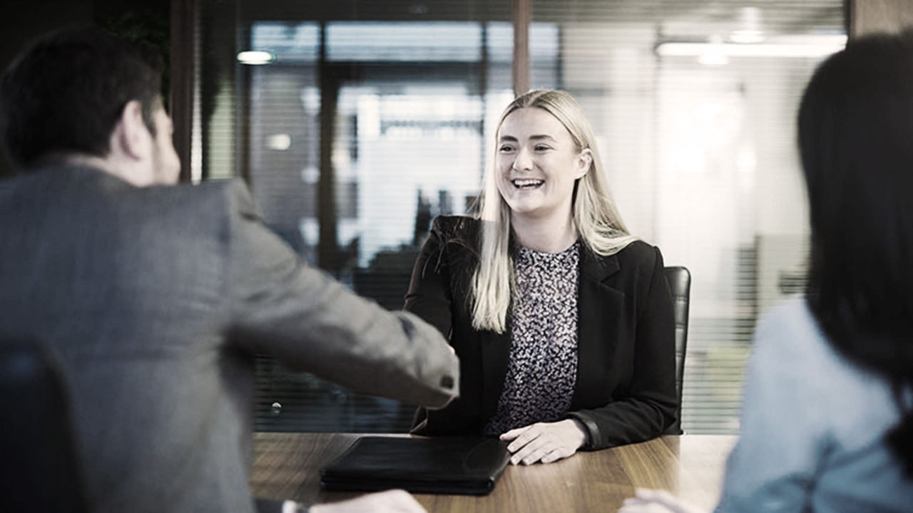 A woman and man shaking hands in an office.