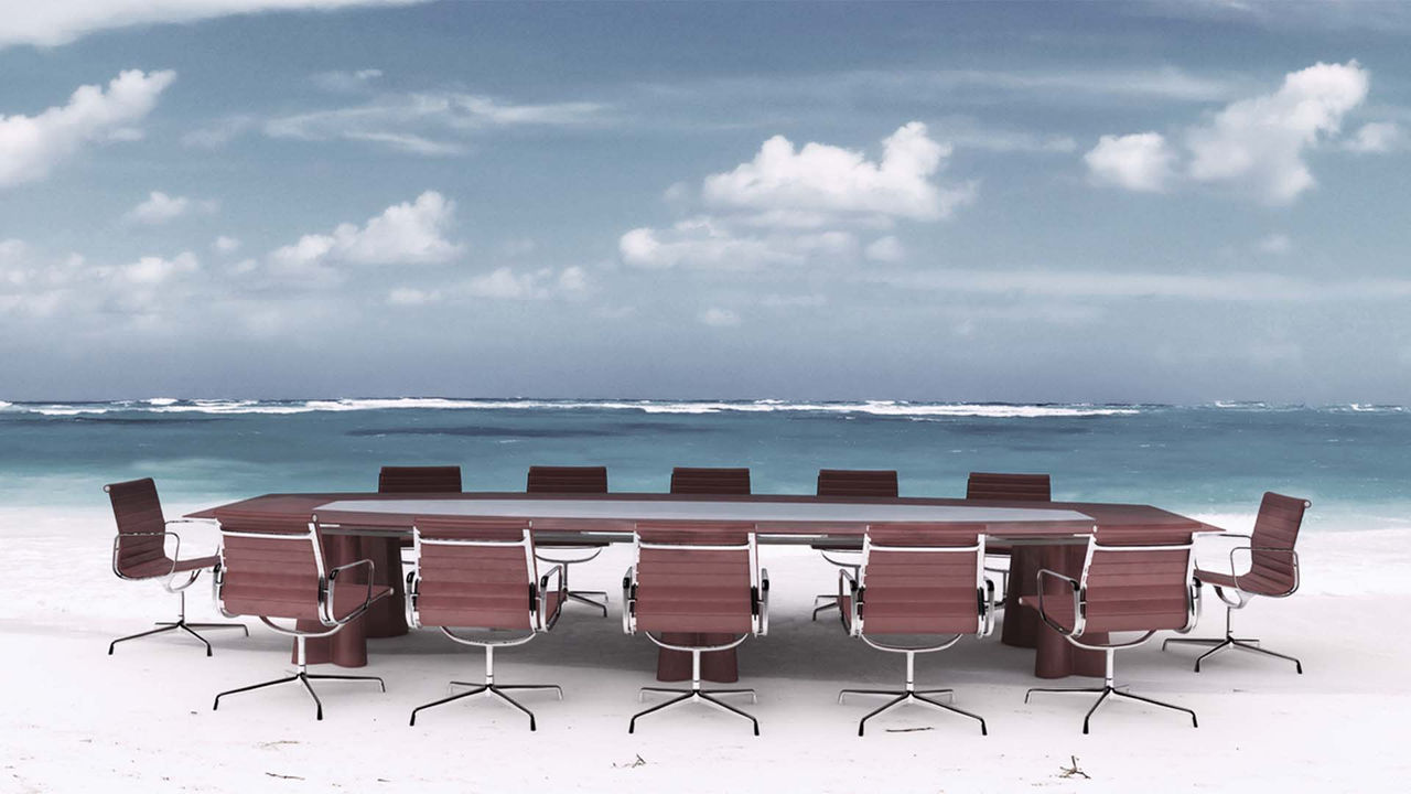 A conference table with chairs on the beach.