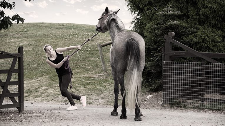 A black and white photo of a woman riding a horse.