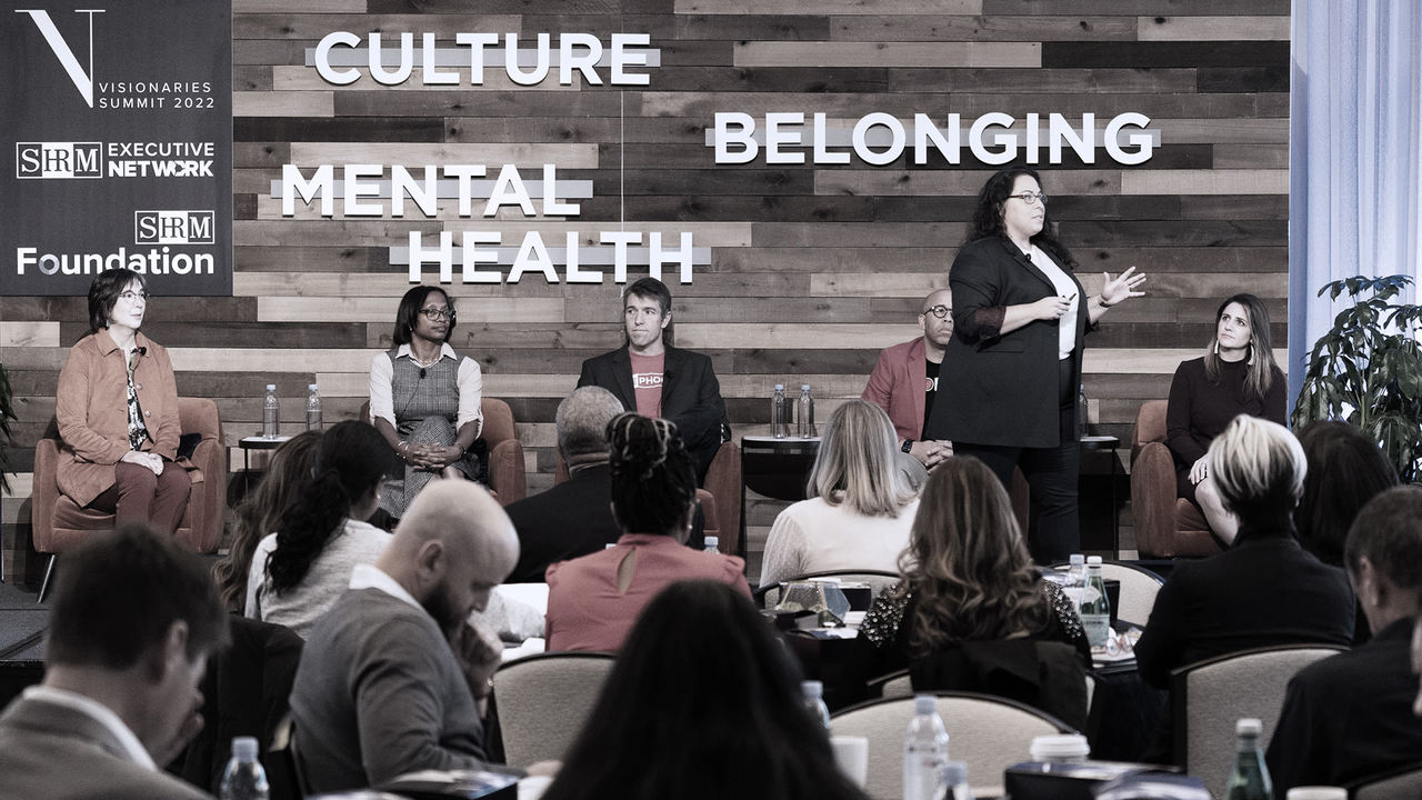A group of people sitting at a table with the words culture belonging mental health.