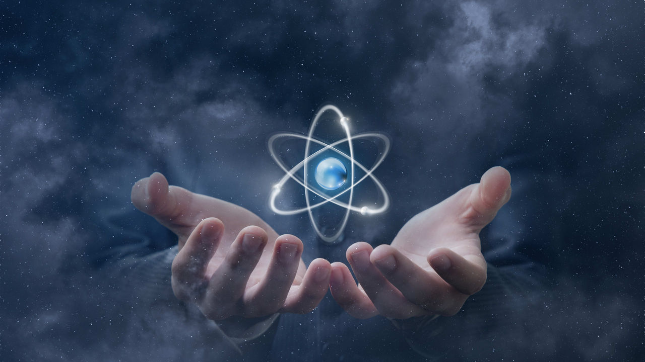 A man's hands with an atomic symbol in them.
