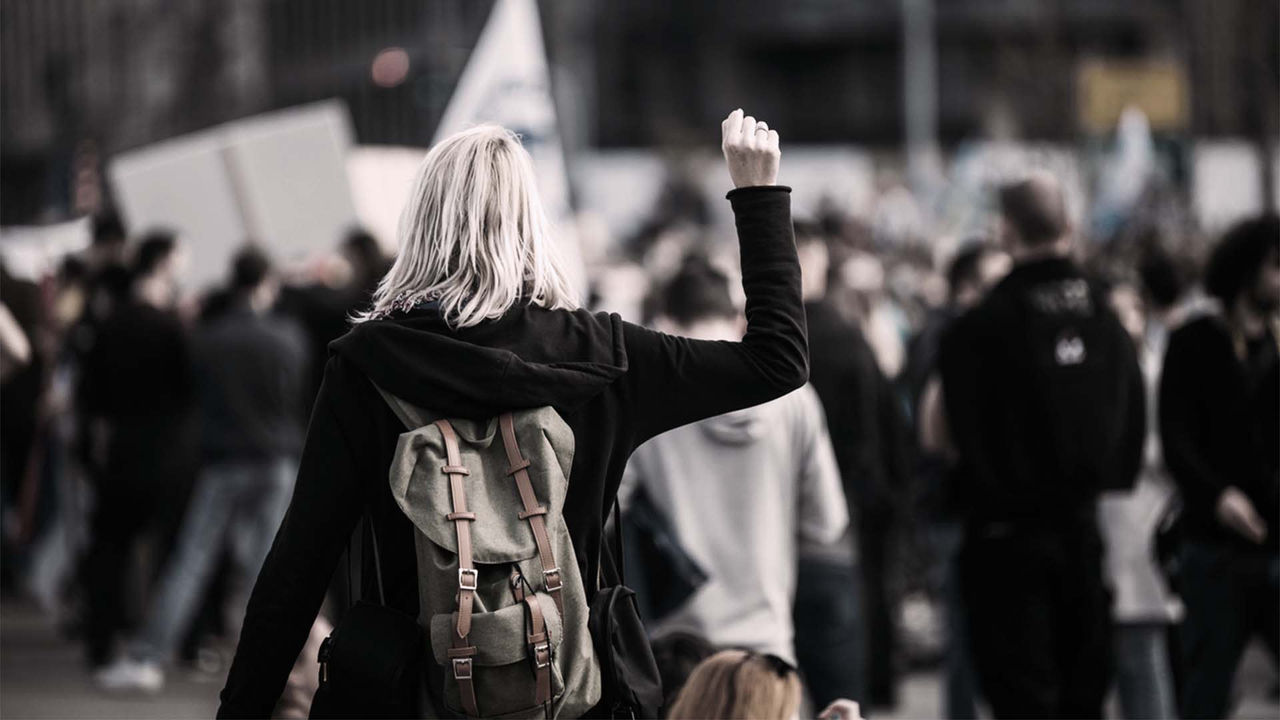 A woman with a backpack in a crowd of people.