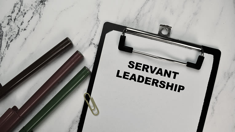 A clipboard with the word servant leadership on it.