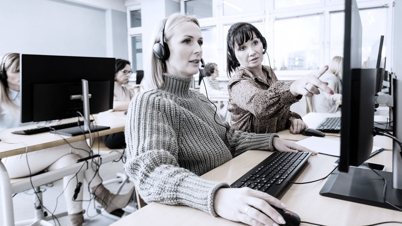 Two women working on computers in a call center.