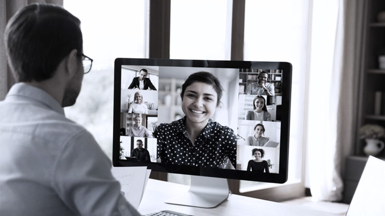A man is on a video call with several people on a computer screen.