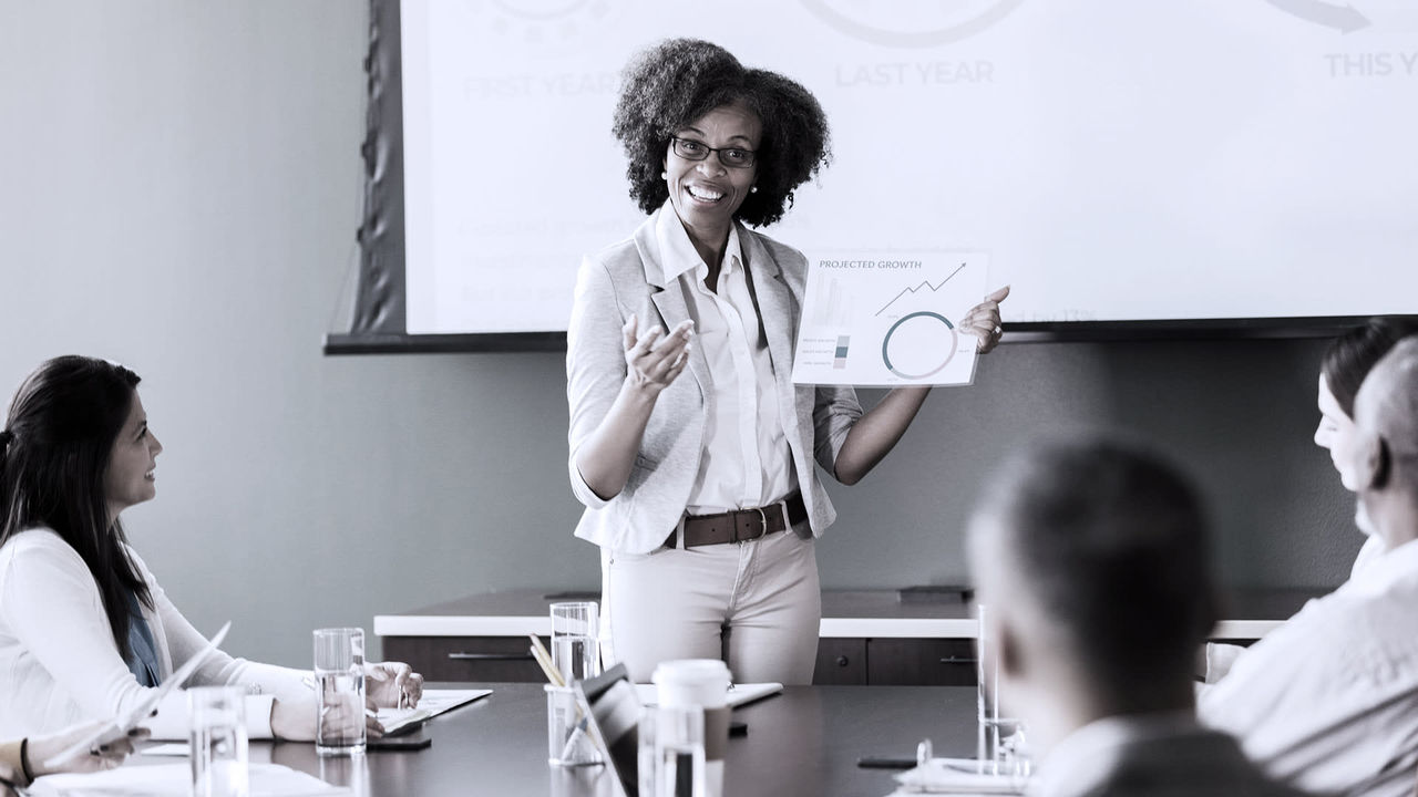 A woman giving a presentation to a group of people in a conference room.