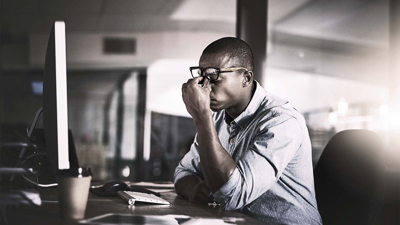 A man is sitting at a desk looking at a computer screen.