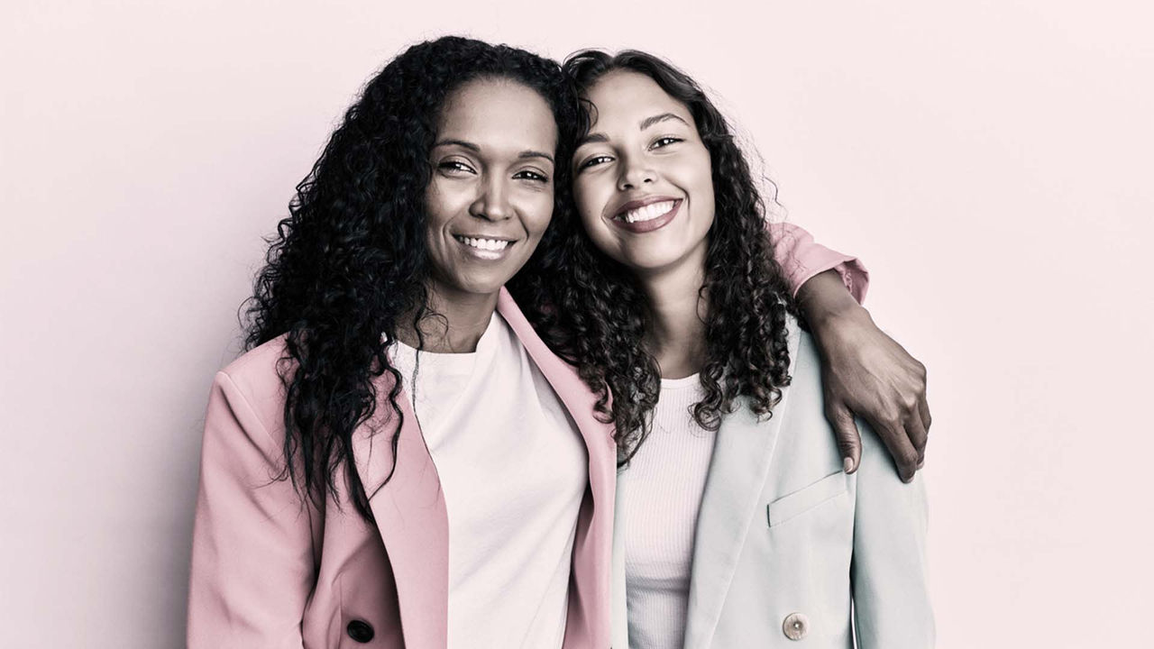 Two women in pink blazers posing for a photo.