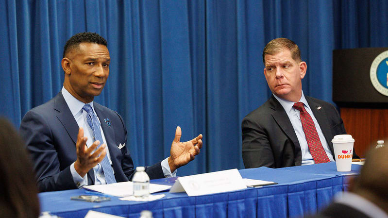 Two men sitting at a table talking to each other.
