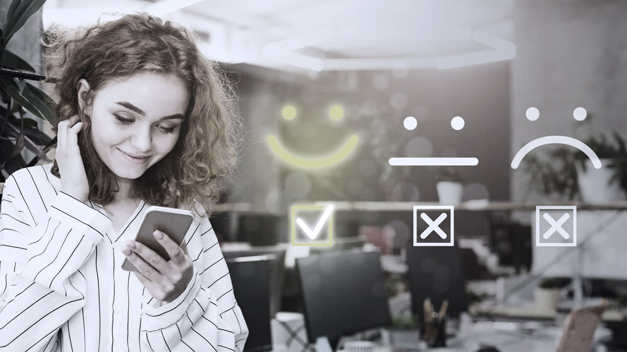 A woman is looking at her phone with a smiley face on it.