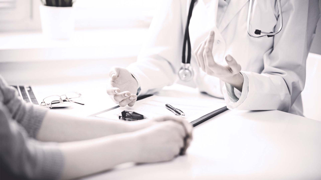 A doctor is talking to a patient at a desk.